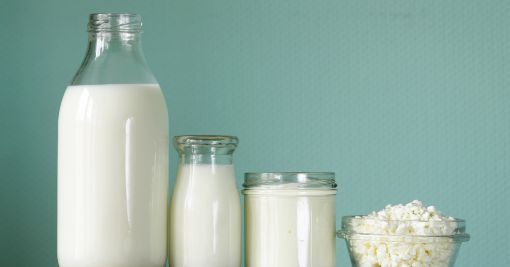 Various jars of dairy products, like milk, yogurt, and cottage cheese are lined up against a light blue background