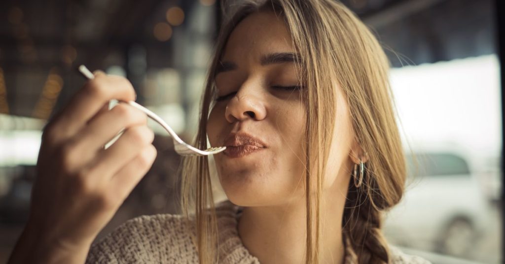 A woman pulls a fork away from her mouth after taking a delectable bite of something sweet, Ways to Stop Sugar Craving