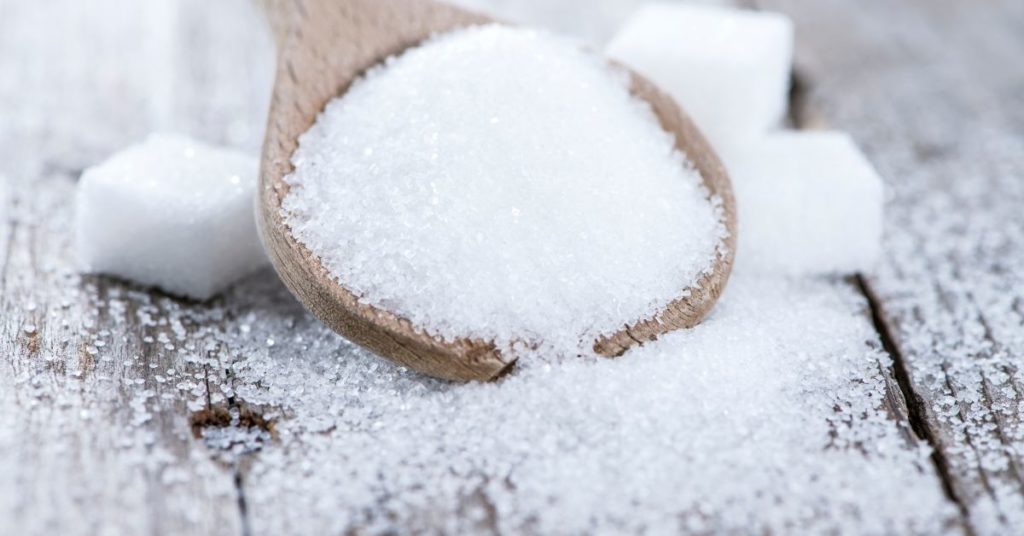 A wooden spoonful of loose sugar rests next to several sugar cubes, Ways to Stop Sugar Craving