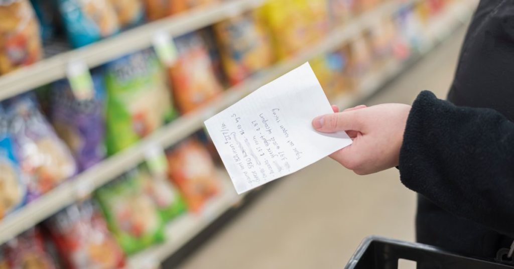 A woman shops with a grocery list in her hand