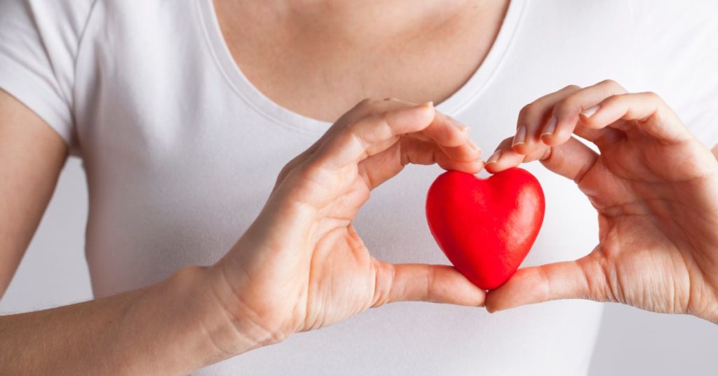 A woman's hands hold up a small foam heart