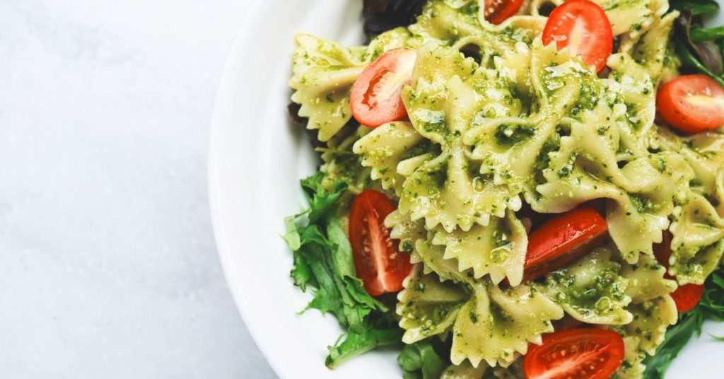 Bowtie pasta topped with pesto and tomatoes in a large bowl