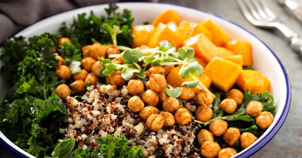 Cooked quinoa grain bowl topped with roasted chickpeas, sweet potatos, and kale
