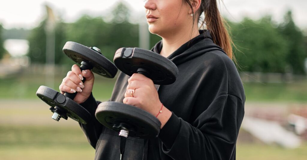 A woman lifts weights in an outdoor setting