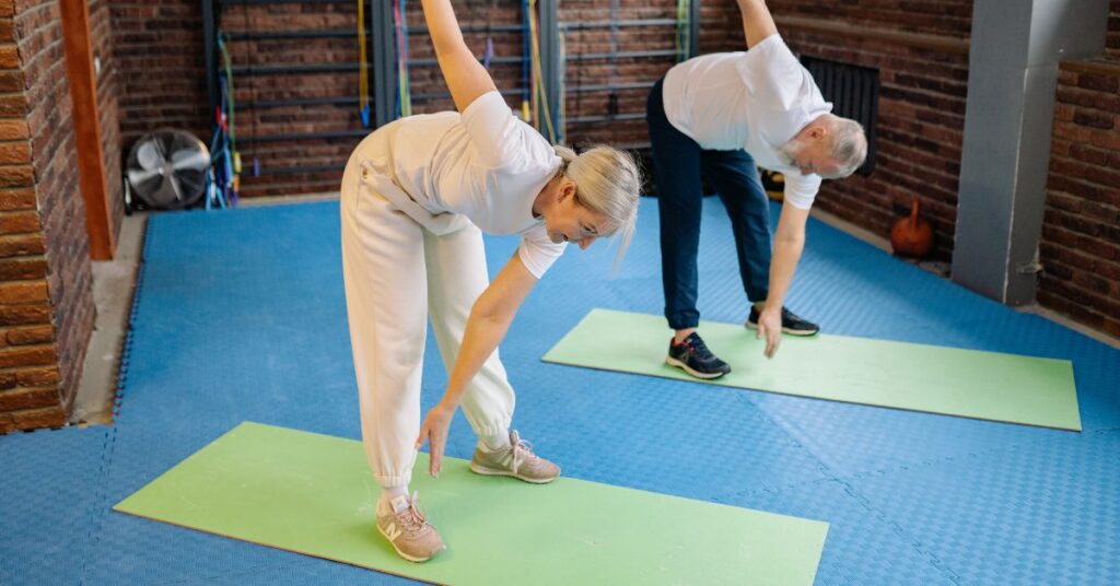 Man and woman stretching on yoga mats, Why do I lose weight when I eat MORE