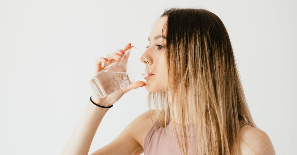 Woman sips water out of a glass cup