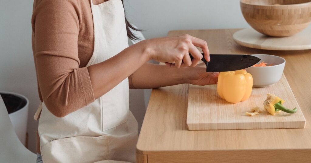 Woman's hands chop a pepper on a cutting board