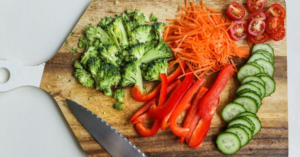 A cutting board with chopped broccoli, carrots, peppers, tomatos, and cucumber, menopausal weight gain