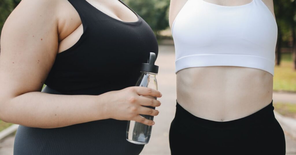 Close up of two women's bodies in tank tops about to go for a run outside. One is larger than the other. There is a bottle of water in one's hand, menopausal weight gain