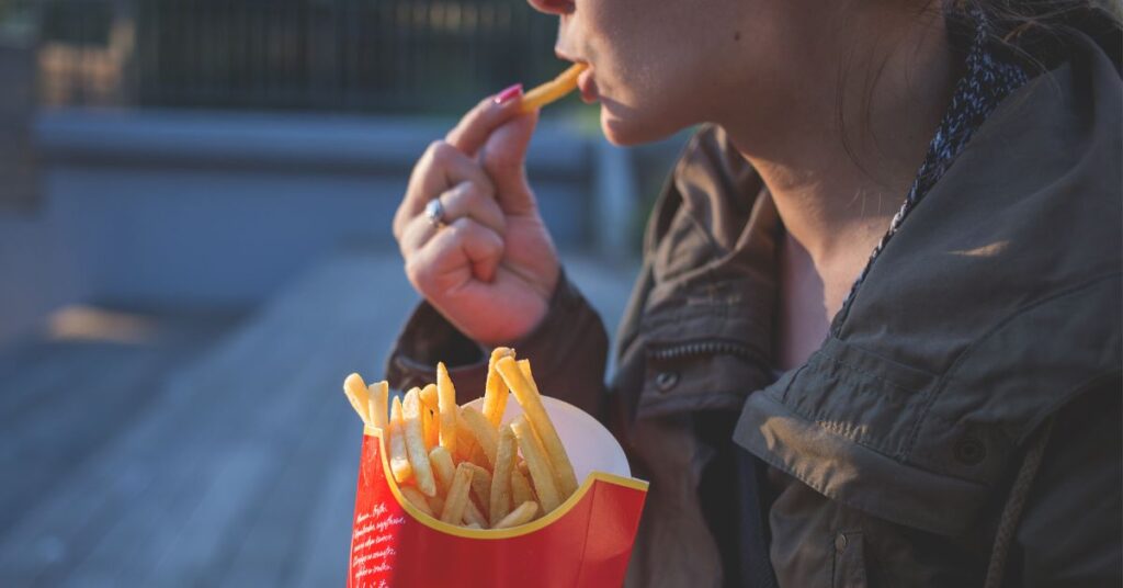 Woman eats french fries, How to Stop Cortisol Weight Gain
