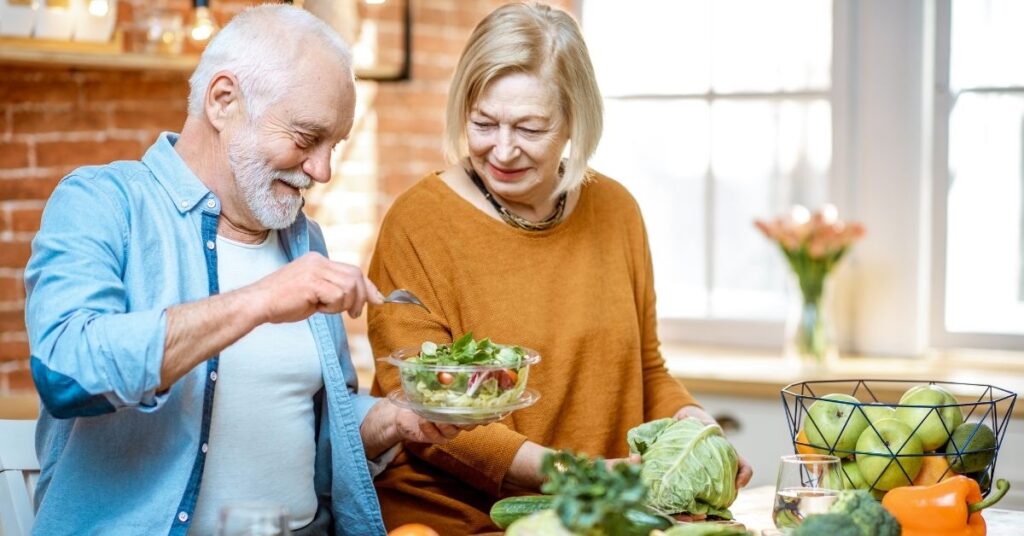 An older couple makes a healthy salad in their kitchen