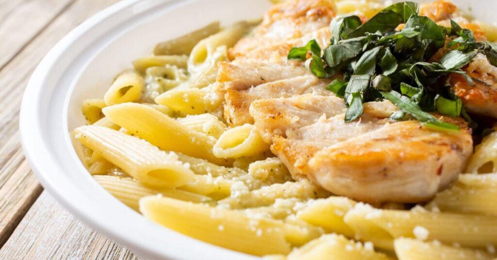 A sliced chicken breast and chopped basil rest atop a plate of pasta, long term weight loss management