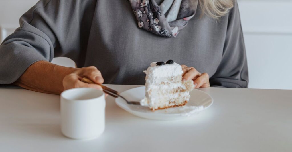 A grey-haired woman takes a bite of a 3-layer cake, Mindful eating journal