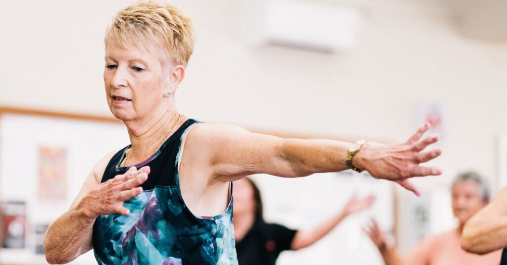 A short-haired older woman takes part in a zumba class