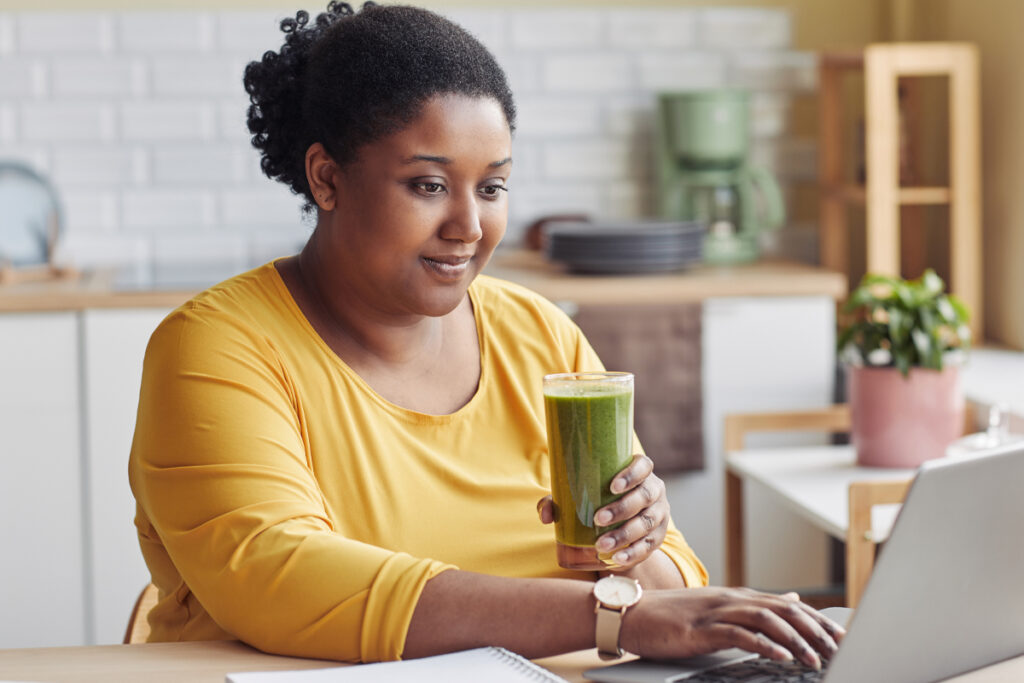 woman drinking a smoothie at her laptop