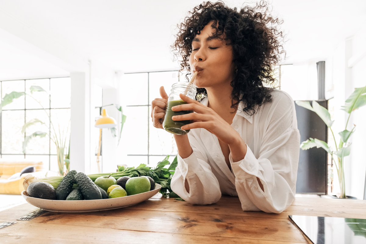 woman drinking green smoothie in the kitchen to fight inflammation