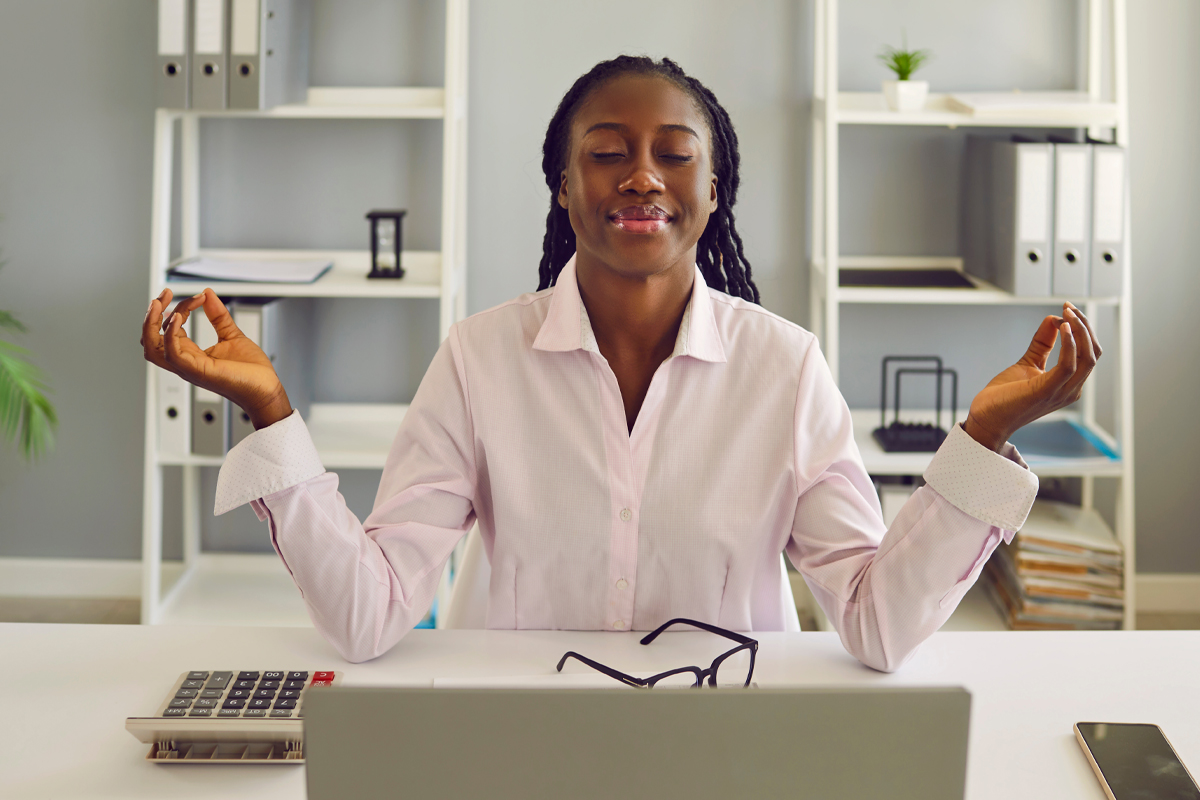 woman taking a break from busy day to practice yoga at desk