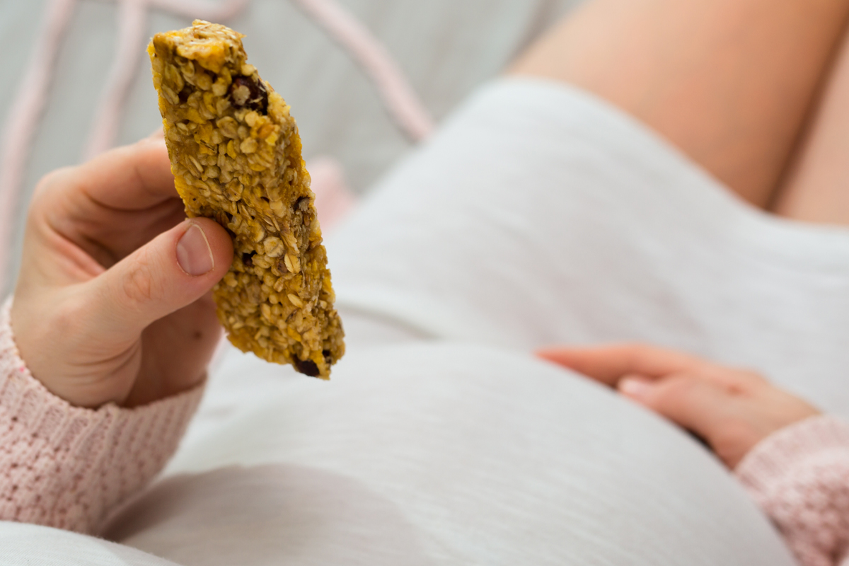 pregnant woman eating protein bar for energy