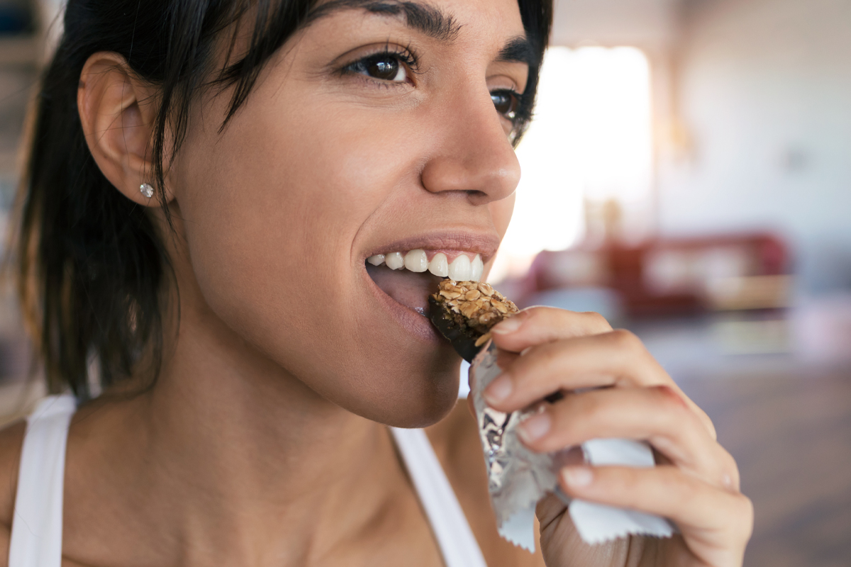 woman enjoying protein bar after a workout