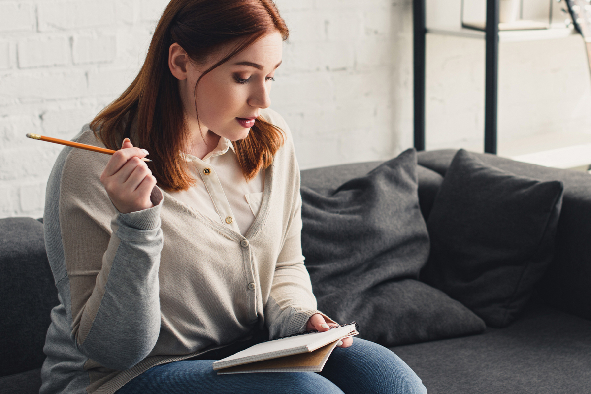 woman writing her weight loss goals in a notebook - sustainable weight loss concept