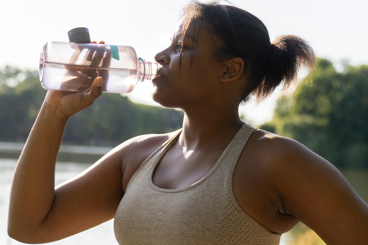 woman drinking water to stay hydrated after a walk