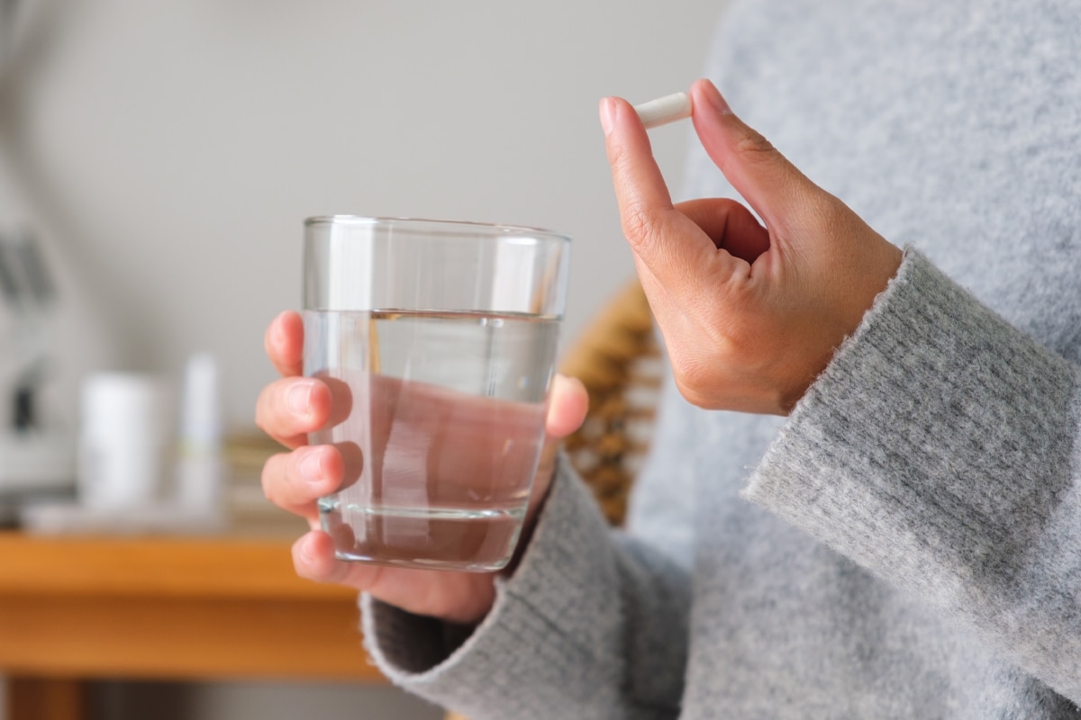 woman taking vitamins or medicine with a glass of water