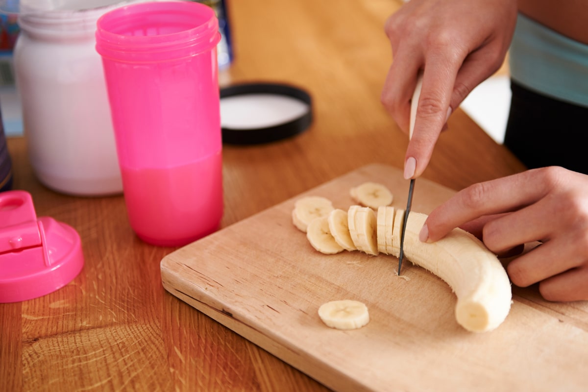 woman slicing a banana for her smoothie